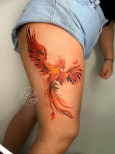 a woman's thigh with a tattoo of a red and yellow bird on it