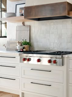 a stove top oven sitting inside of a kitchen next to white cabinets and counter tops