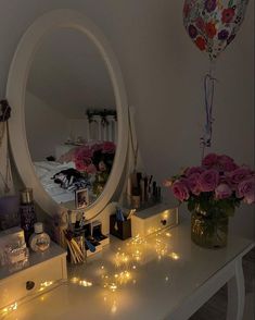 a mirror sitting on top of a white table next to a vase filled with flowers