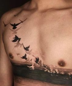 a man's chest with birds flying over the water