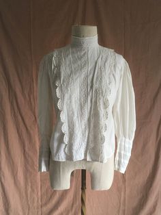 "vintage early 1900s antique true vintage blouse white cotton embroidered cotton lace mother of pearl buttons (except bottom button which is something else, maybe plastic) eyelet detail lace trim right of center buttons up front hidden under lace flap the button placement makes this seem to be originally meant for breast feeding  tie back hook eye back neck mutton chop sleeves front hem is longer than back hem good vintage condition  considering age w/signs of wear mended holes, fray, light tea/rust color stains here and there the buttons had wear around them enough for me to put patches under the buttons for re-enforcement all the buttons don't match but are of the era patches around back tie area patches around neck area repairs by me wearable measures, lying flat, shoulder-15 1/2\" ches Victorian Cotton Fitted Blouse, Fitted Victorian Cotton Blouse, Victorian White Cotton Top, Victorian Style White Cotton Top, Victorian Cotton Tops With Lace Trim, Victorian Cotton Top With Lace Trim, Victorian Cotton Blouse With Lace Collar, Vintage Cotton Blouse With Lace Top, Vintage Long Sleeve Blouse With Broderie Anglaise