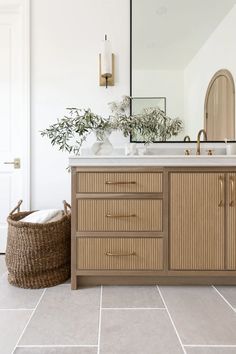 a bathroom with a sink, mirror and basket on the floor in front of it