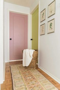 a pink door is in the hallway next to a rug