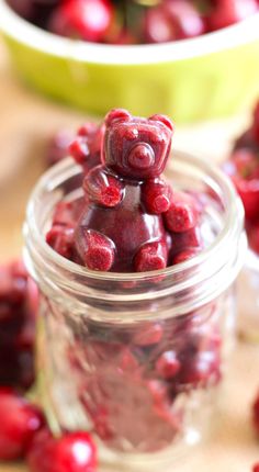 there are cherries in the glass jar and on the table next to each other