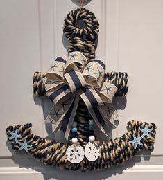 a decorative anchor made out of rope with blue and white decorations hanging on the front door