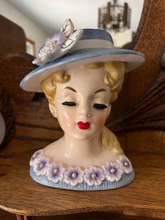 a ceramic figurine wearing a hat with flowers on it's head sitting on a shelf