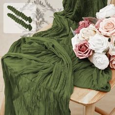 a bouquet of flowers sitting on top of a wooden table next to a green blanket