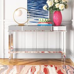 a vase with white flowers on top of a table in front of a painting and rug