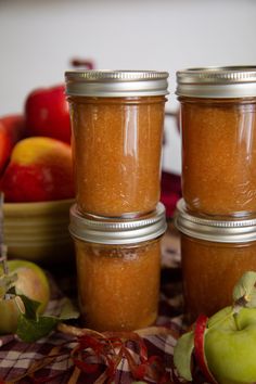 three jars filled with apples sitting on top of a table