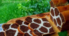 slices of giraffe print bread on a wooden cutting board with green grass in the background