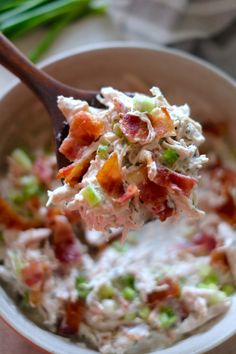 a wooden spoon full of potato salad with bacon and celery on it,