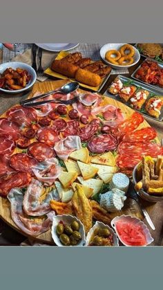 a large platter of meats and cheeses on a table with other foods