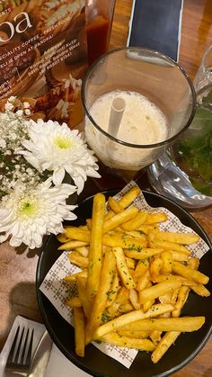 french fries on a plate next to some flowers and a cookbook with the recipe