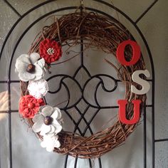 a wreath with flowers and the word osu hanging on a wrought iron door frame