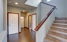 a staircase leading to the first floor in a home with wood floors and white doors