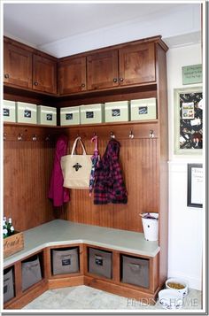 an organized mud room with wooden cabinets and drawers