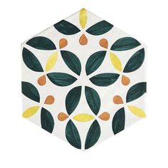 a hexagonal tile with orange and green leaves painted on the top, in white background