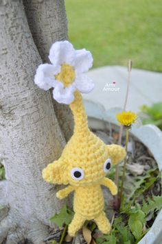 a crocheted yellow stuffed animal holding a white flower