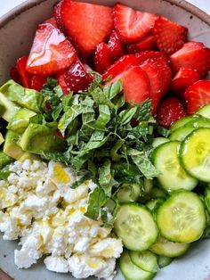 strawberries, cucumbers, and cheese are arranged in a bowl