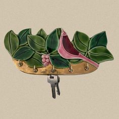 a bird sitting on top of a key holder with leaves and berries painted on it