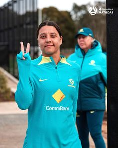 two women in blue jackets are making the peace sign with their hands while one woman stands behind them