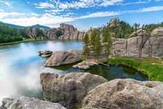 the lake is surrounded by large rocks and trees