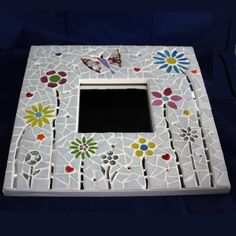 a white mosaic frame with flowers and butterflies on it