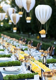 a long table is set with plates and hot air balloons in the shape of lanterns