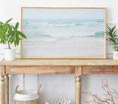 a wooden shelf with some plants on top of it next to a painting and potted plants