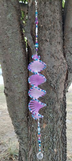 a tree with beads hanging from it's bark and a glass bead necklace attached to the branch