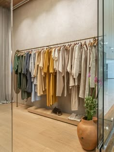 a clothing rack with clothes hanging from it's racks in front of a glass wall