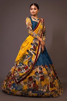 Blue base attached cancan lehenga with humans and animals kalamkari hand painted patterns and embroidery. Paired with padded blue blouse embroidered with glass beads and yellow printed dupatta with contrast border. - Aza Fashions Coat Dresses For Women Traditional, Kalamkari Lehenga Designs Latest, Yellow And Blue Lehenga, Ikkat Half Saree Designs, Penkalamkari Lehanga, Pen Kalamkari Lehangas, Kalamkari Lehengas, Kalamkari Lehenga Designs, Kalamkari Blouse Designs Latest