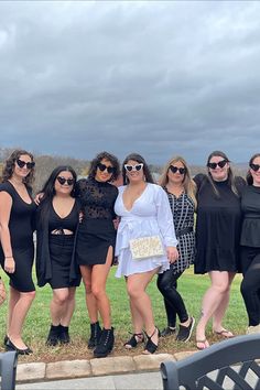 a group of women standing next to each other on top of a grass covered field