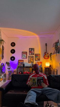 a man sitting on top of a couch in a living room next to a guitar