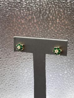 Gorgeous ladies emerald stud earrings designed in 14 karat solid yellow gold.  6 fine round Emeralds are set in a petal design surrounding a round white diamond in the center of the flower.  Feminine and classy earrings that look lovely on any woman. Weight:  1.8 grams Diameter:  ⅜" Please See Our Video Remember - If you're purchasing for yourself or a gift for a loved one, buy with confidence.  We Guarantee Everything We Sell!  SKU # E776 Emerald Stud Earrings, Classy Earrings, Emerald Earrings Studs, Floral Earrings, Solid Yellow, Designer Earrings, Jewelry Earrings Studs, White Diamond, Favorite Jewelry