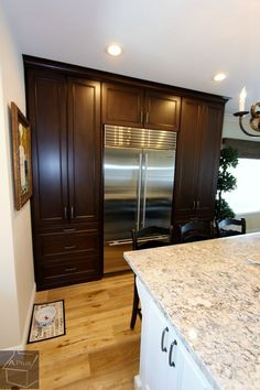 a kitchen with marble counter tops and stainless steel refrigerator in the center, surrounded by wooden cabinets