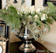 a vase filled with white flowers sitting on top of a table next to a mirror