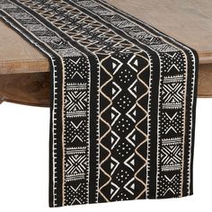 a black and white table runner on top of a wooden table with an intricate design