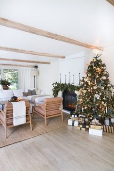 a living room filled with furniture and a christmas tree in front of a fire place