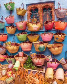 many baskets are hanging up on the wall in front of a building with blue walls