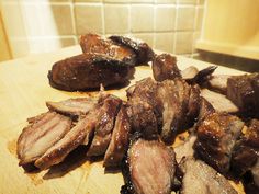 sliced meat sitting on top of a wooden cutting board