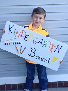 a young boy holding a sign that says, kindergartn is bound with crayons