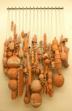 a group of wooden objects hanging from strings on a white wall in an art gallery