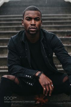 a man sitting on the steps in front of stairs with his hand on his knee