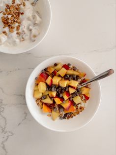 two bowls filled with cereal and fruit on top of a white marble countertop next to each other