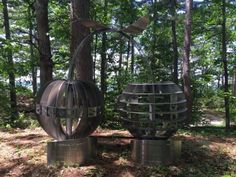 two metal sculptures sitting in the middle of a forest