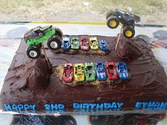 a birthday cake with monster trucks and cars on it