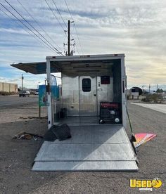 an enclosed trailer is parked on the side of the road with its door open and luggage in it