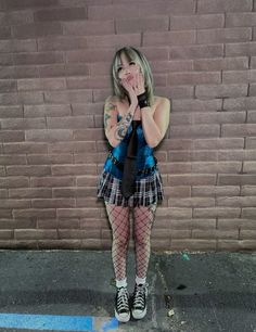 a young woman standing in front of a brick wall with her mouth open and tongue out