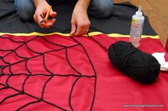 a person sitting on the floor making a spider web design with yarn and glues